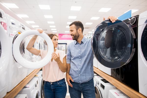 A man and a woman compare front load washers in a store