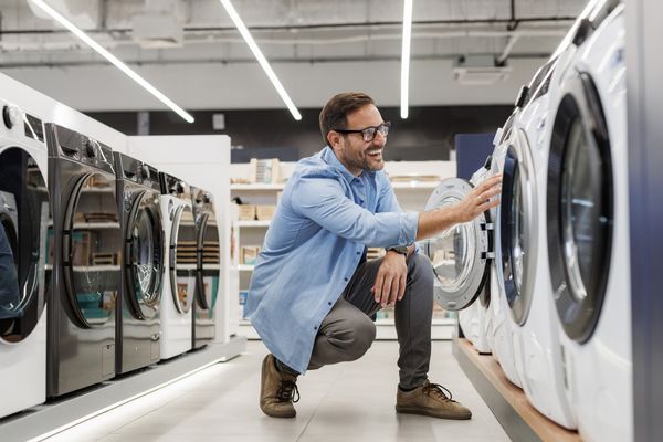 A smiling man inspecting a front load washer