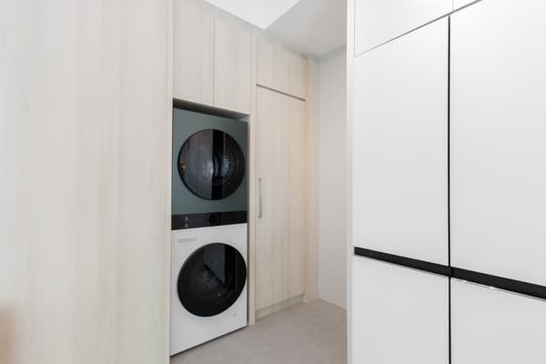A white and green stacked washer dryer unit in wooden cabinetry