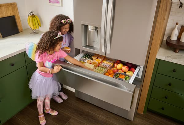 Two girls grabbing items out of the LG LF29H8330S refrigerator 