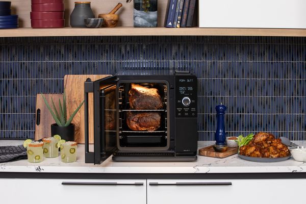 Black countertop smart oven smoking meat with open door