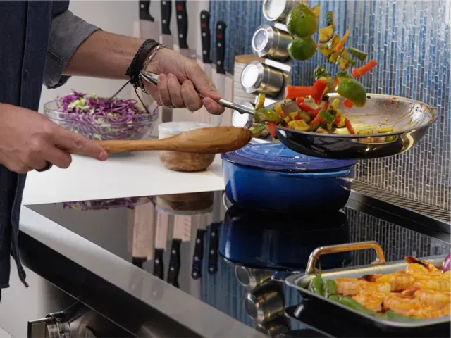 Close view of a man cooking dinner on a black induction cooktop