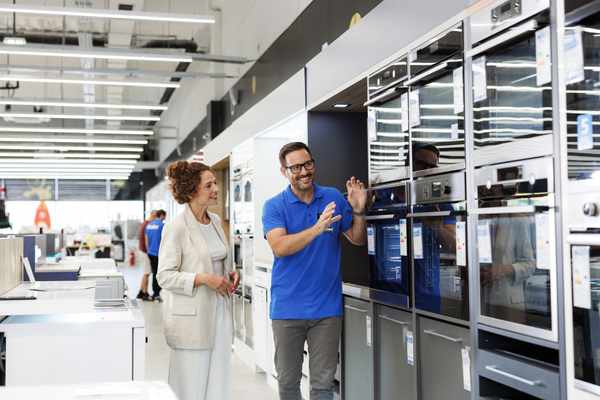 An appliance salesman showing off an oven to a woman