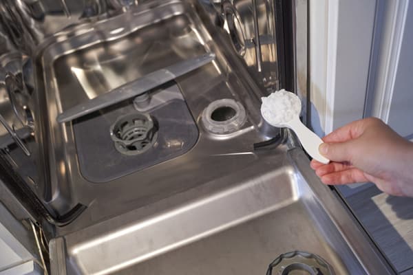iStock Credit: Elena Safonova A person adding baking soda to a dishwasher