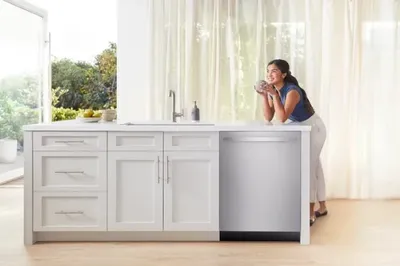 A woman smiling over the Bosch Benchmark SHX9PCM5N dishwasher