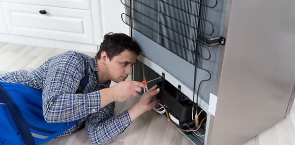 An appliance repairman fixing a refrigerator