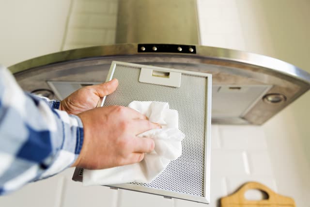 Front view of a person cleaning a range hood filter