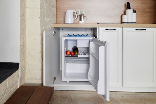 An open compact refrigerator in a cabinet 