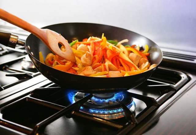 Close view of stir fry being cooked on a wok on a gas stove Close view of stir fry being cooked on a wok on a gas stove