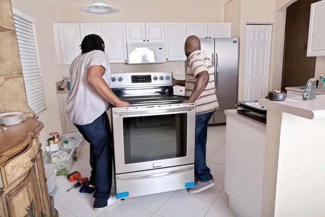 Front view of two men installing a slide in range in a modern kitchen renovation
