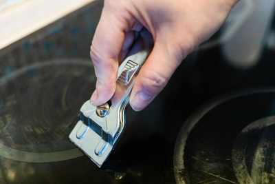 A person using a razor on a glass cooktop