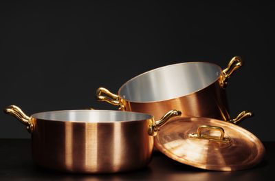A set of copper cookware against a black background 