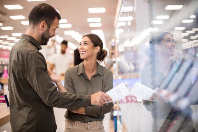 Front view of a couple of people chatting in an appliance showroom Front view of a couple of people chatting in an appliance showroom