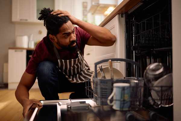 iStock Credit: Drazen Zigic A man looking worried into a dishwasher