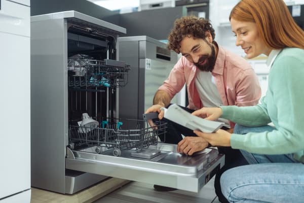 iStock Credit: Lajst A woman and a man reviewing a dishwasher’s specs.