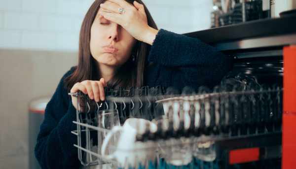 iStock Credit: Ali Mrioued A frustrated woman crouched near an open dishwasher