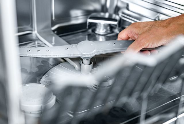 Close view of a person removing a dishwasher spray arm