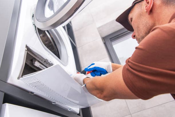 Front view of a man repairing a dryer Front view of a man repairing a dryer