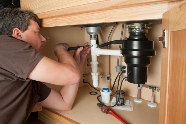 A man fixing a garbage disposal 