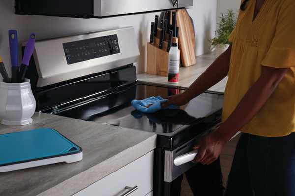 A person cleaning a Frigidaire range