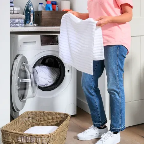 A woman removing towels from the GE GFQ14ESSNWW washer dryer 