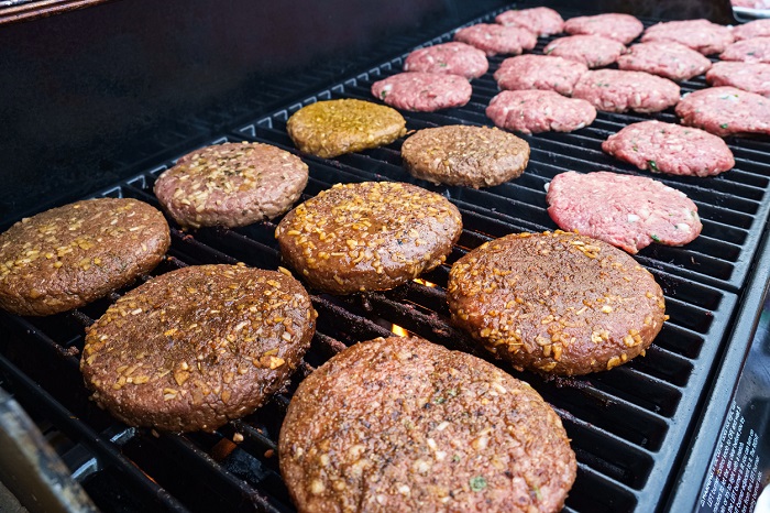 RAUL RODRIGUEZ Rows of seasoned burgers on a gas powered grill.