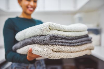 A smiling woman holding a pile of towels 