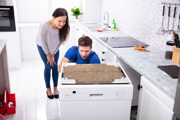 A woman and a technician inspecting a dishwasher  