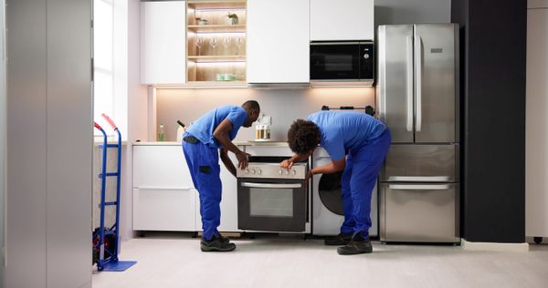 iStock Credit: AndreyPopov Two appliance technicians installing an oven
