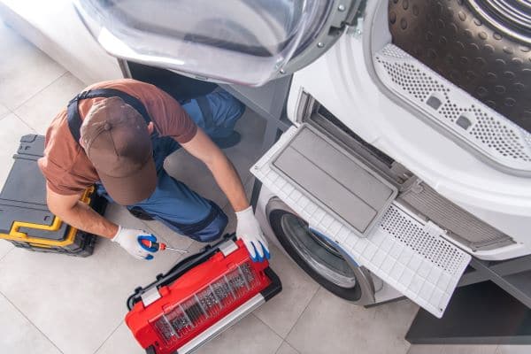 View of a man repairing a dryer View of a man repairing a dryer