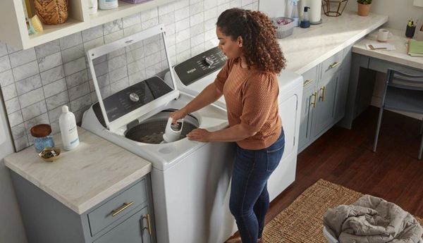 A woman removing the Whirlpool WTW5057LW washer agitator 