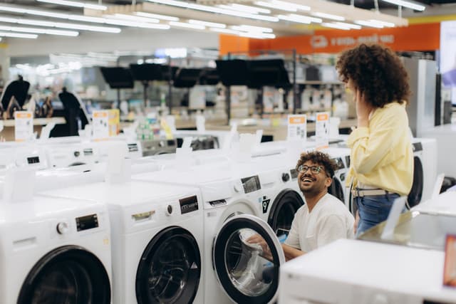 View of a couple shopping for a new washing machine in an applaince store View of a couple shopping for a new washing machine in an applaince store
