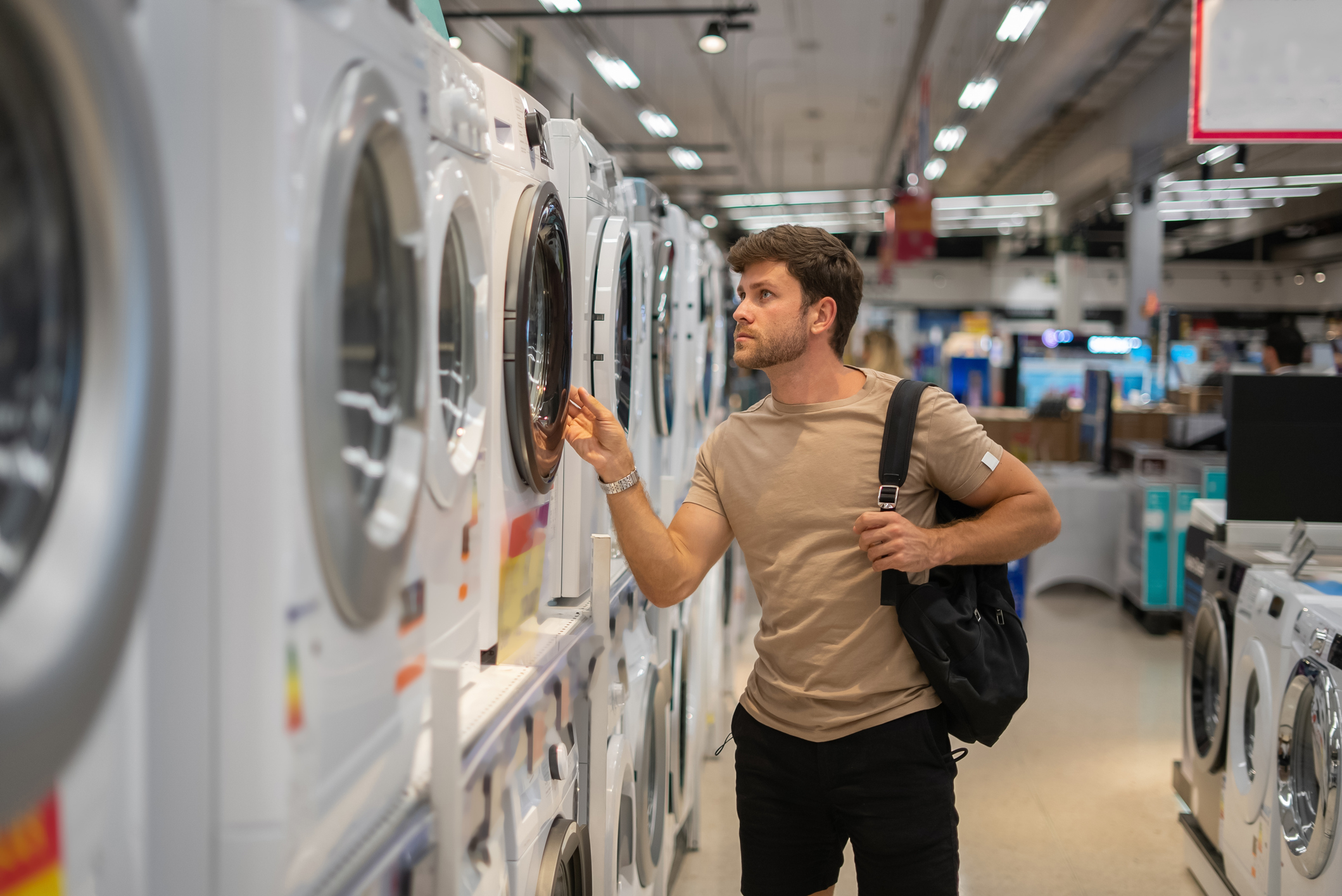 Igor-Kardasov A young man inspecting a front load washer in a store