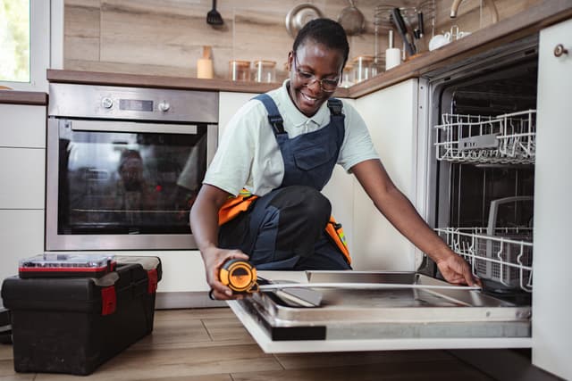 Front view of a handywoman measuring a dishwasher installation Front view of a handywoman measuring a dishwasher installation
