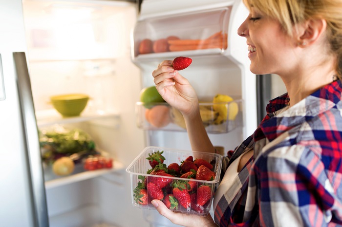 nensuria Young woman pulling strawberries out of the fridge.
