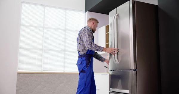 An appliance tech pushing in a refrigerator 