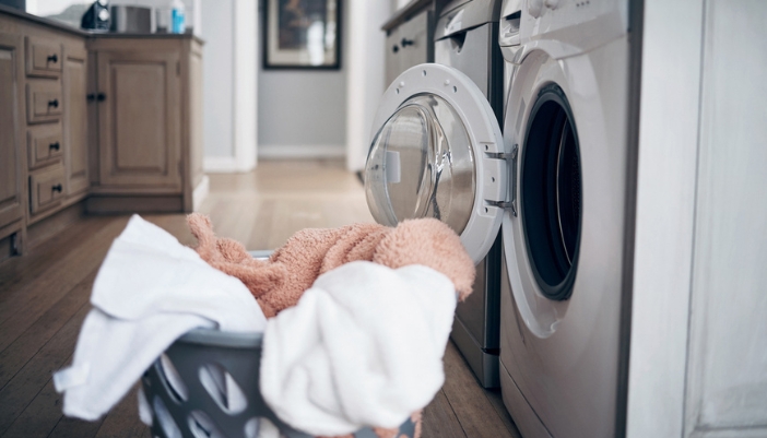 Appl_winter-laundry-tips_1.jpg A laundry basket filled with blankets sits outside an open dryer.