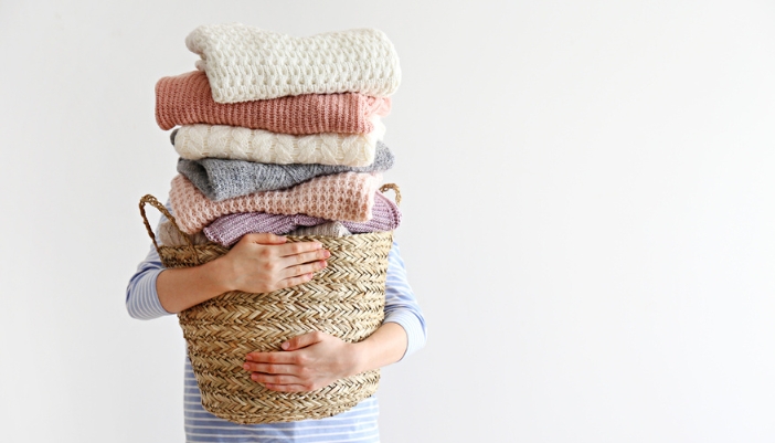 Appl_winter-laundry-tips_3.jpg A person holds a very full basket of folded winter laundry.