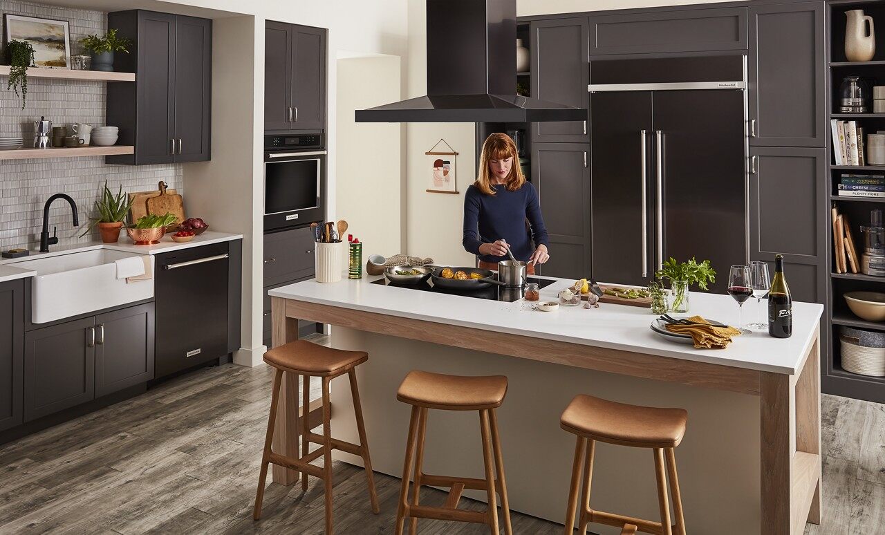 woman cooking in kitchen with black Whirlpool appliances