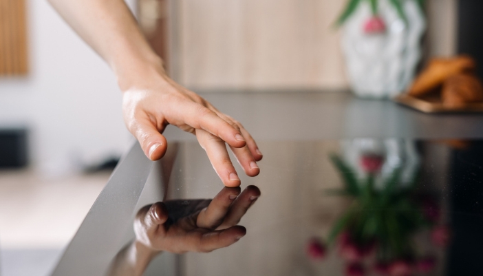 A hand touches a cool induction cook surface.