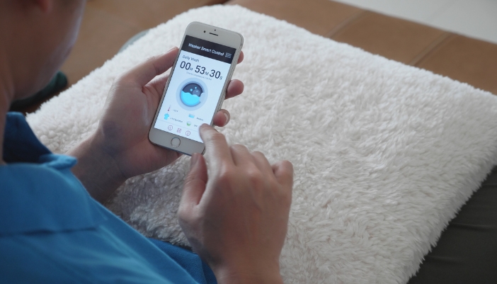 App_Laundry-Tech-Innovations_5.jpg Closeup of someone checking on their washer load with their smart phone