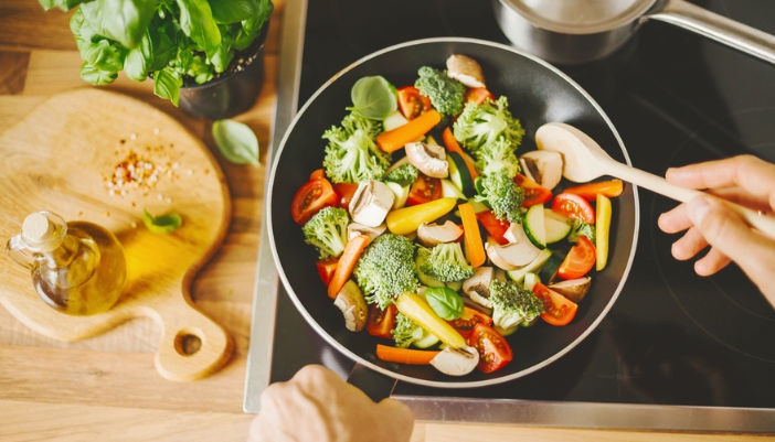 A pan of mixed veggies cooks on an induction cooktop.
