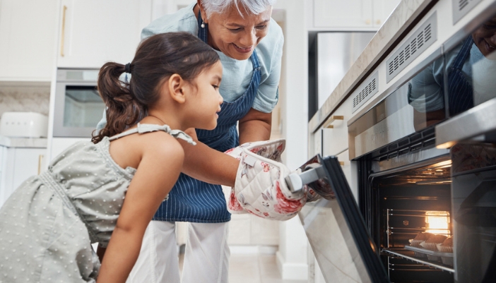 A grandmother and her granddaughter unload an oven together.