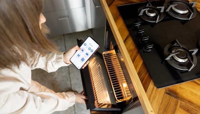 App_Appliance-Shopping-FAQs_3.jpg Woman using her smartphone to operate her smart oven