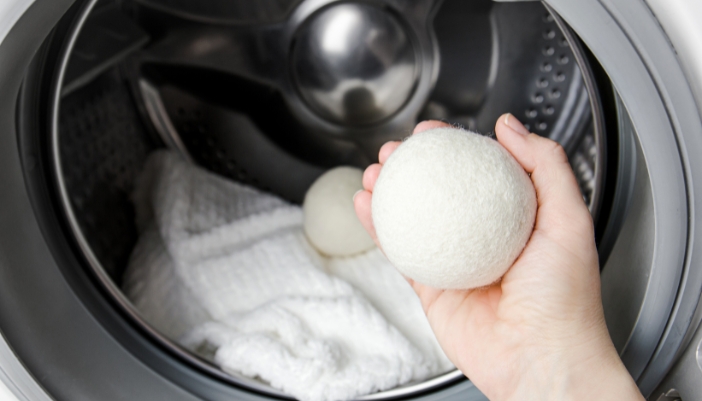 Closeup of someone adding dryer balls to the dryer