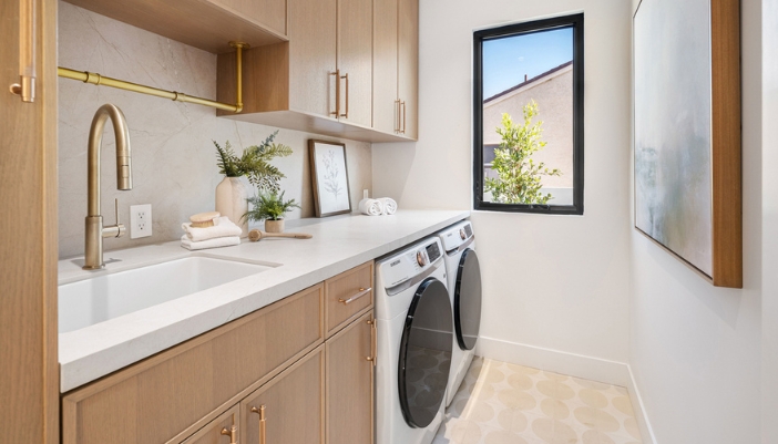 A modern laundry room with warm wooden accents and white appliances.