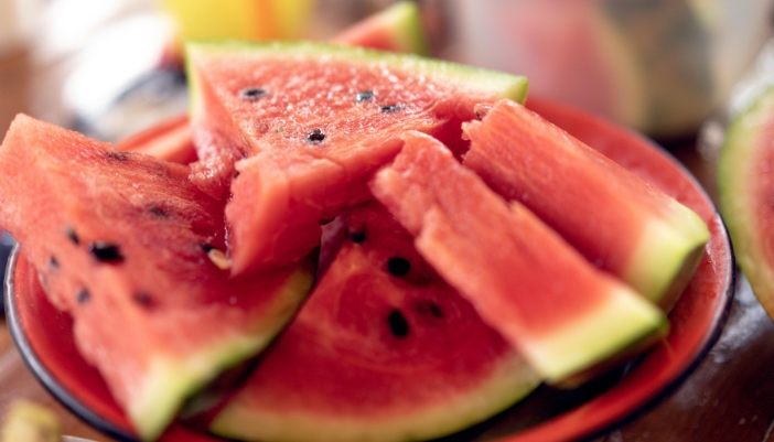 Cut watermelon slices placed on a red platter.