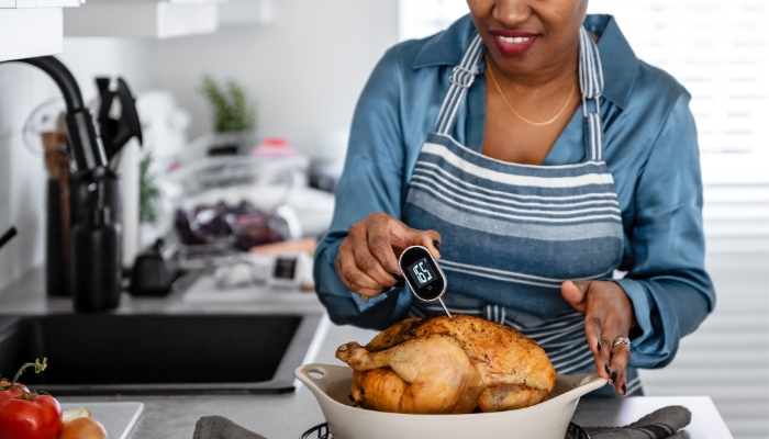 App_Meat-Thermometer_3.jpg Woman inserting a digital meat thermometer into her cooked chicken