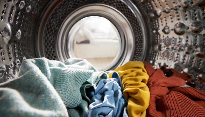 View from inside a stainless steel washer drum holding a small load of colorful knit clothes