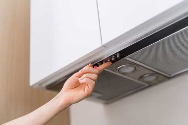 A person selecting a setting on a range hood 